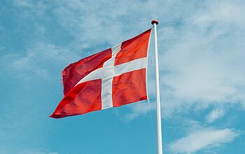 Die dänische Flagge weht vor blauem Himmel.