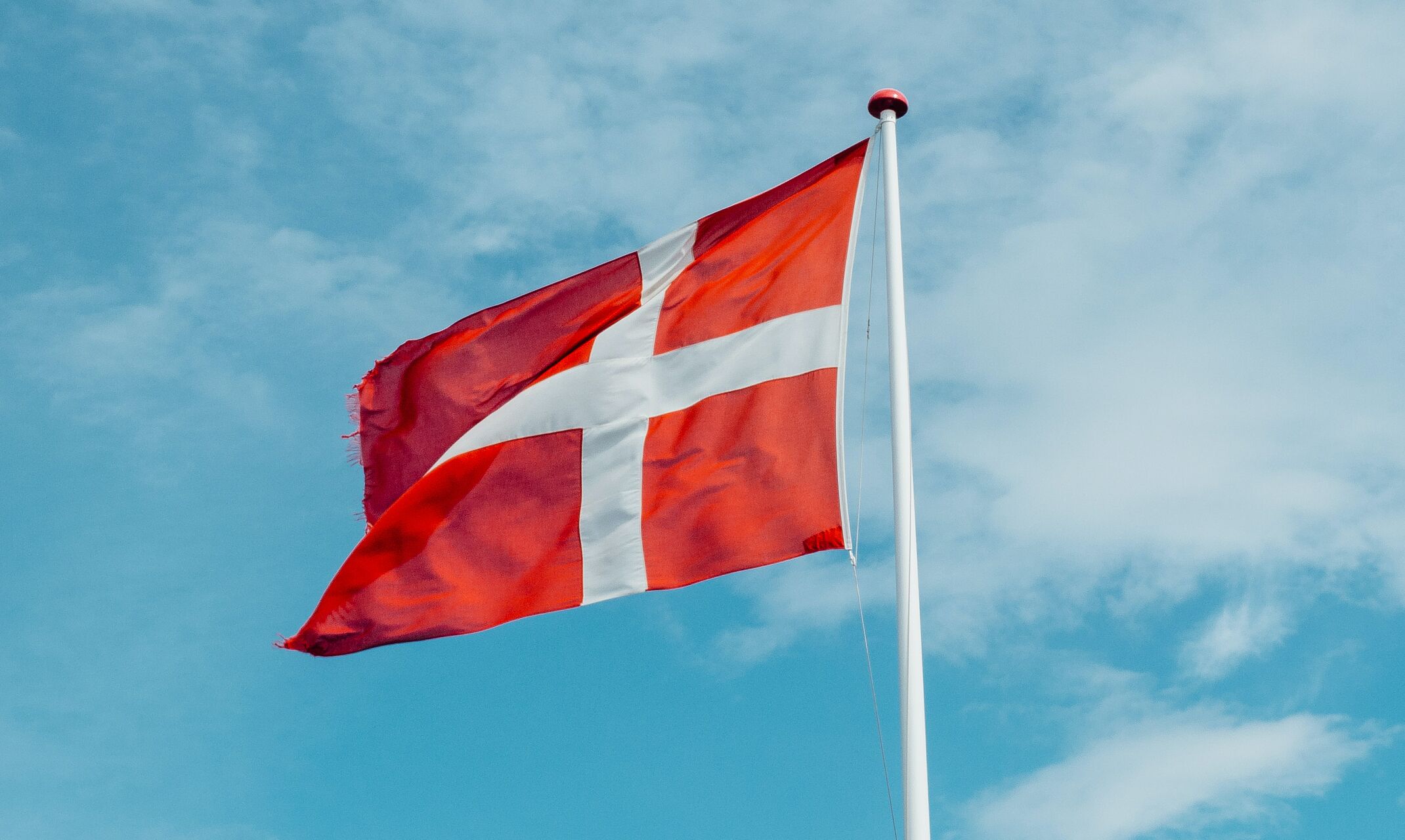 Die dänische Flagge weht vor blauem Himmel.