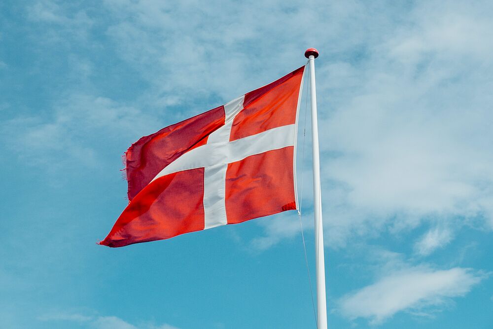 Die dänische Flagge weht vor blauem Himmel.
