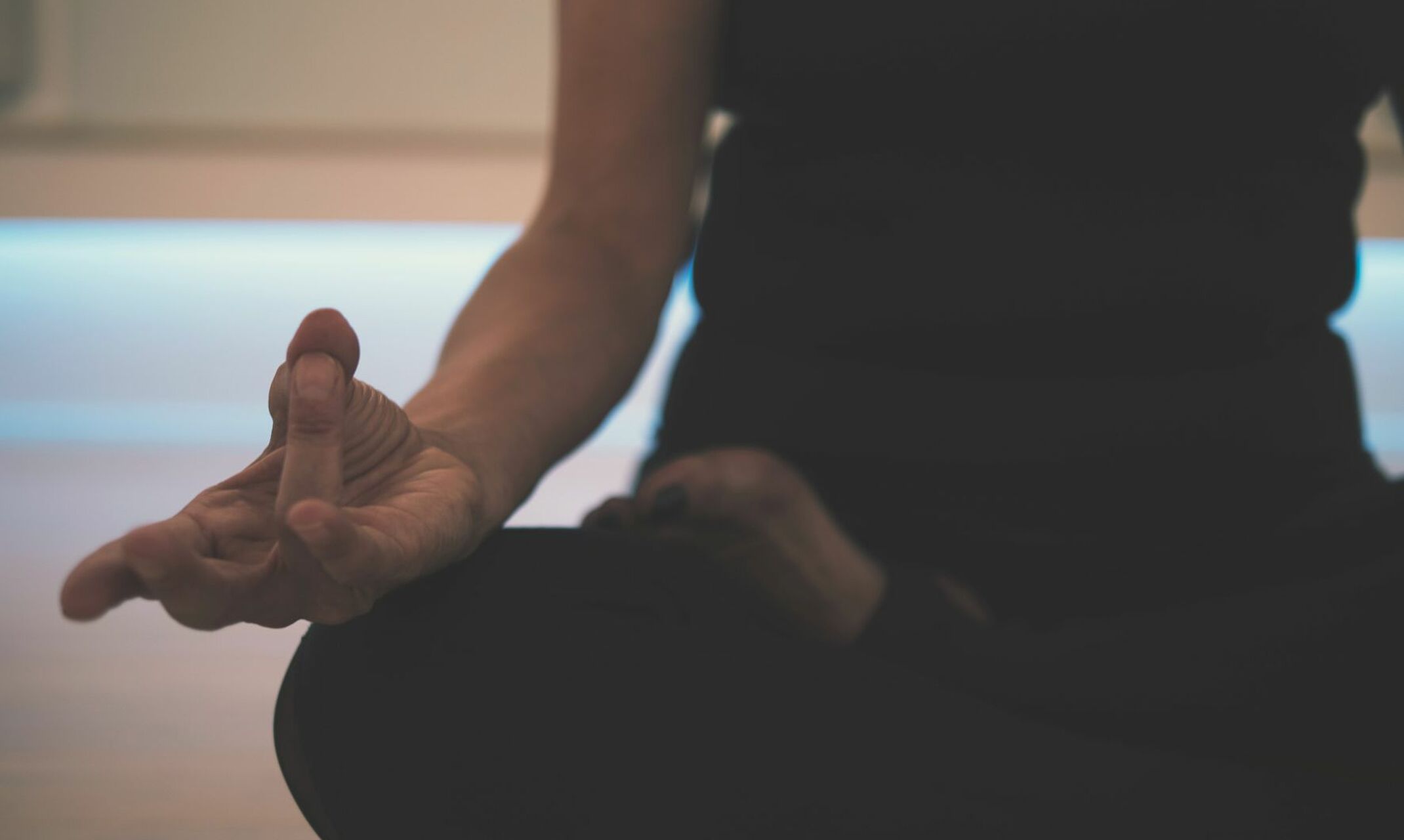 Frau im Schneidersitz mit yoga-typischer Handhaltung.
