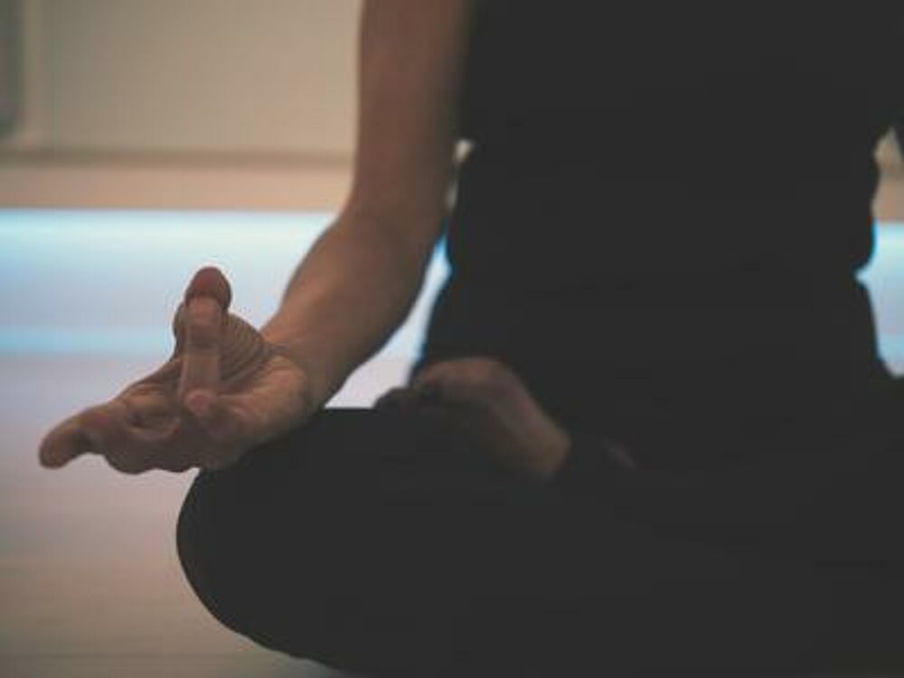 Frau im Schneidersitz mit yoga-typischer Fingerhaltung.