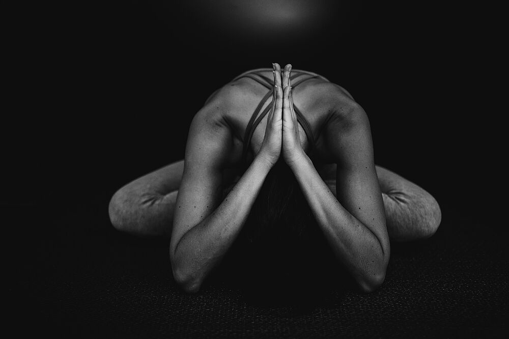 Yogahaltung in der Hocke mit gesenktem Kopf.