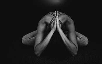 Yogahaltung in der Hocke mit gesenktem Kopf.