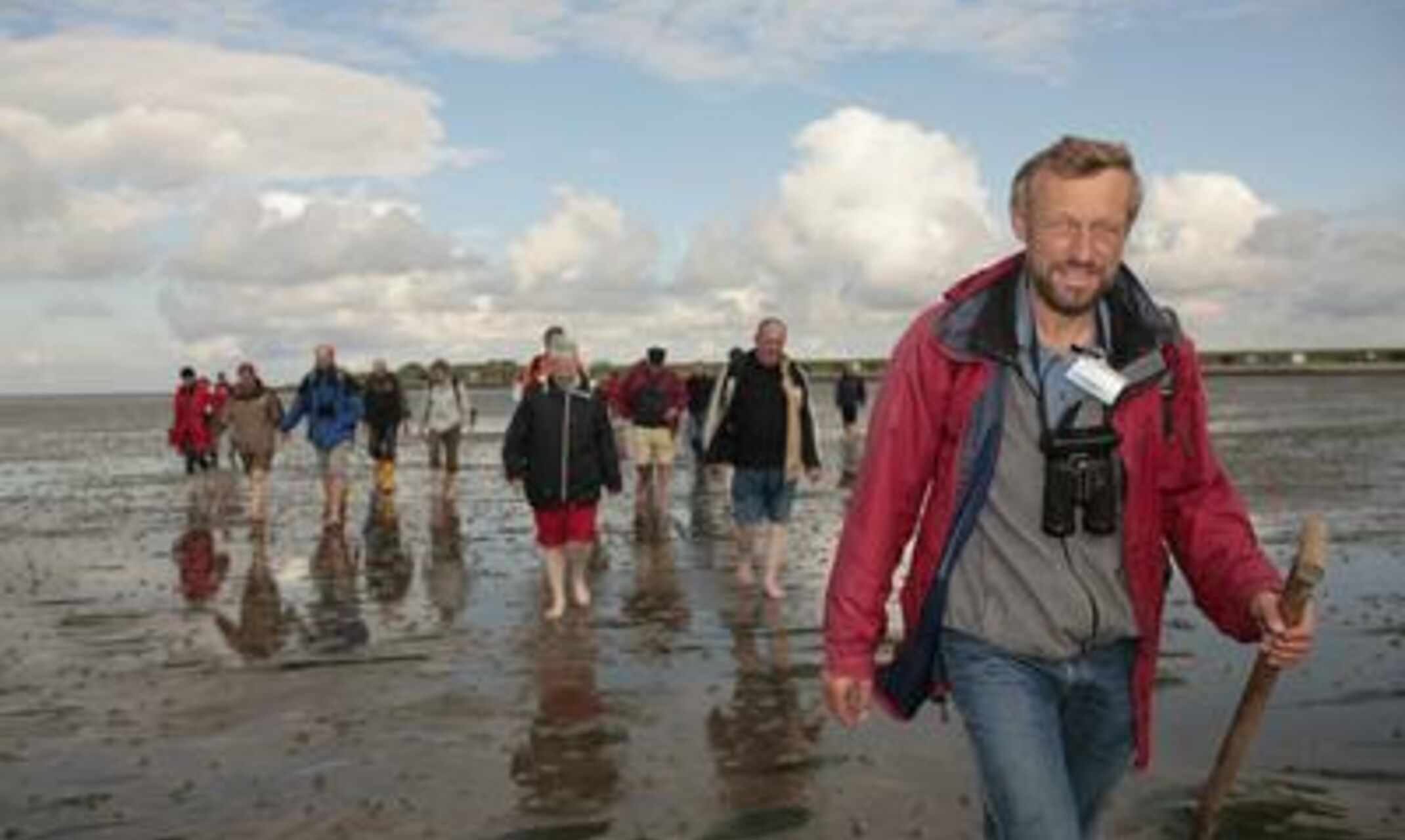 Eine Gruppe Menschen auf Wanderung durch den Schlick des Wattenmeeres.